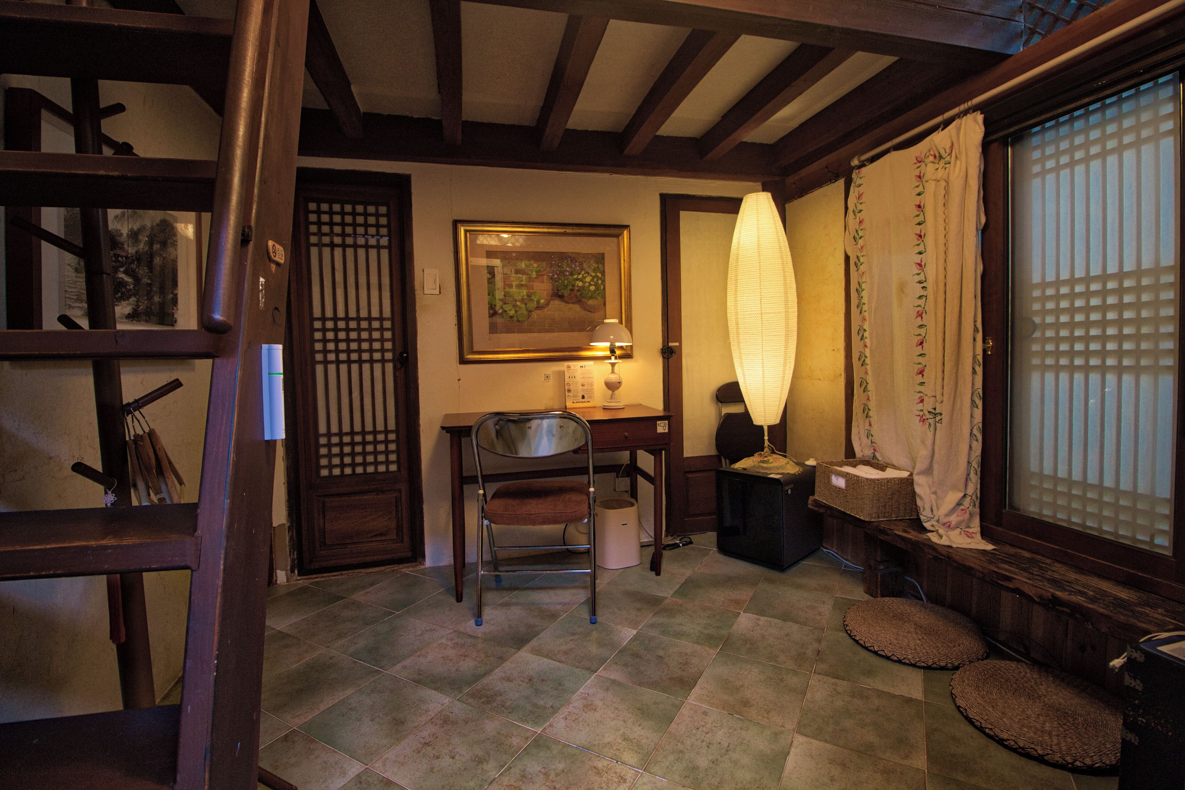 Een traditionele Japanse kamer met tatami vloeren, een shoji scherm, een bureau met lamp en een houten stoel.