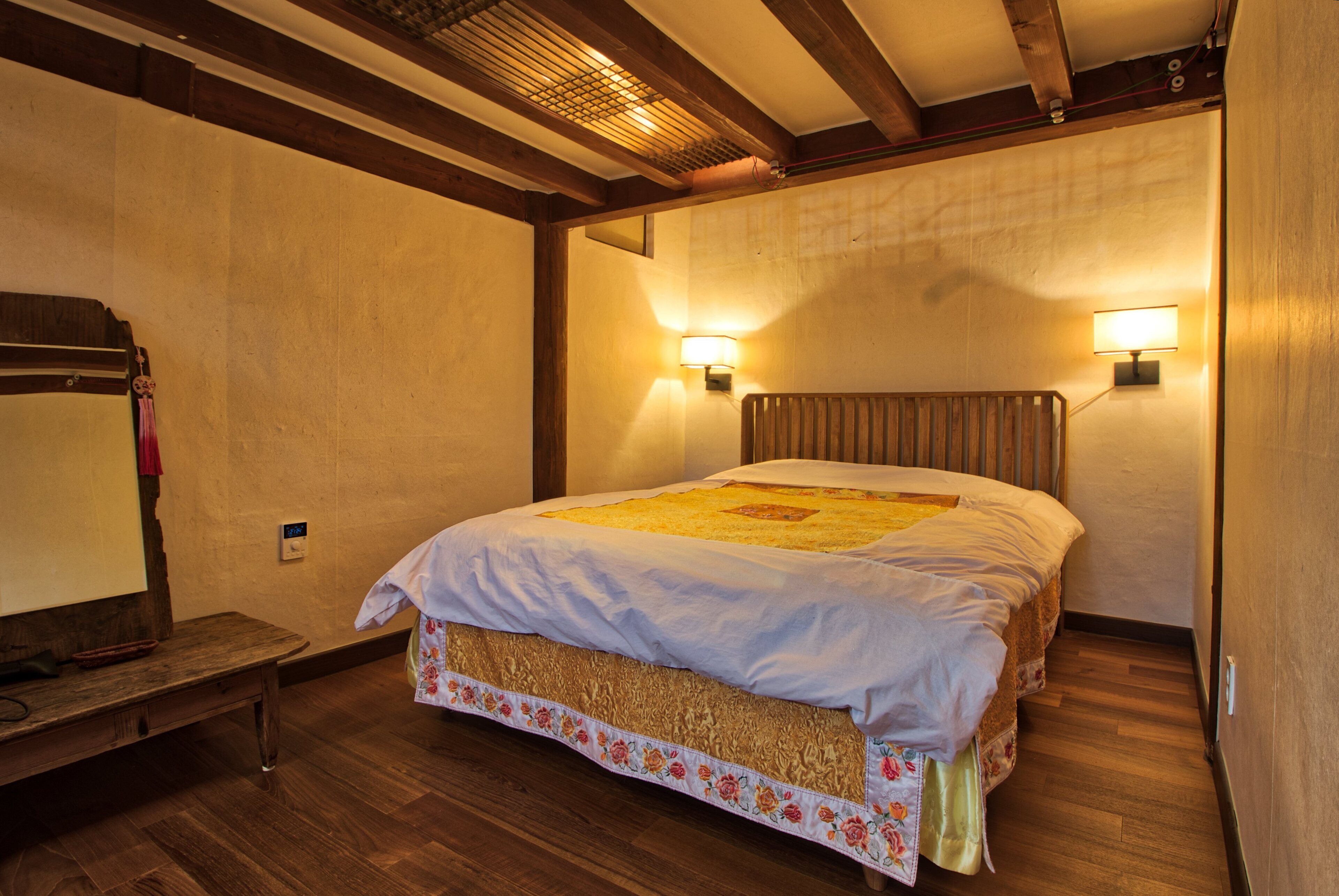 A bedroom with a wooden bed, a bench, and two wall-mounted lamps.