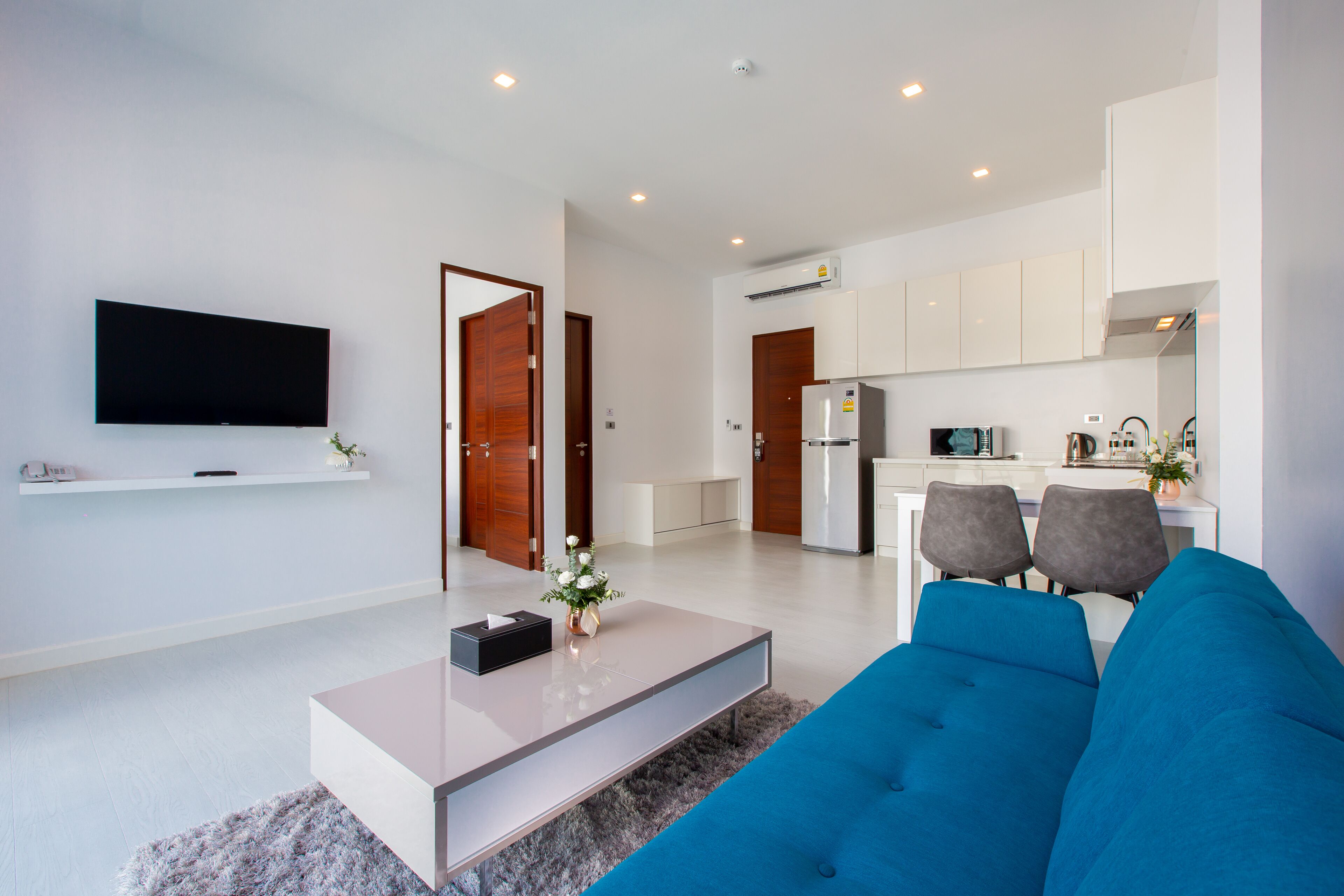 A modern living room with a flat-screen TV, a coffee table, and a blue sofa.