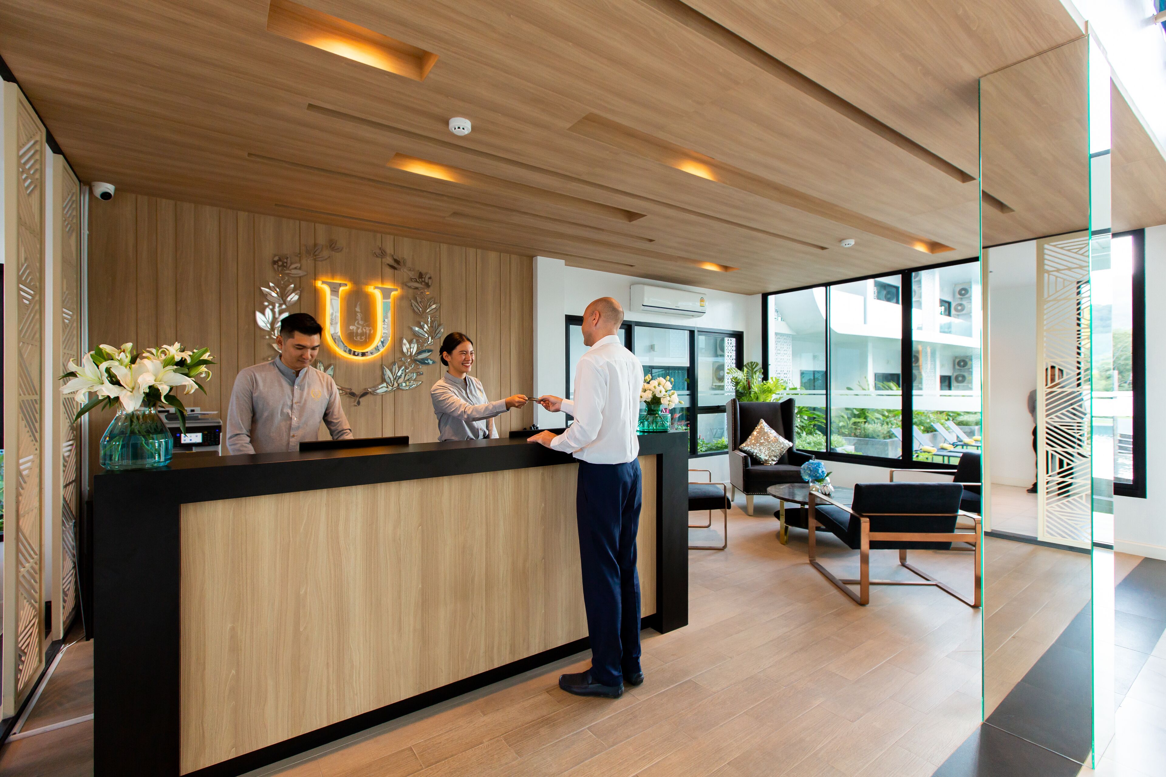 Un espace d’accueil doté d’un comptoir en bois, d’un grand panneau lumineux en forme de « U » et d’un aménagement intérieur moderne.