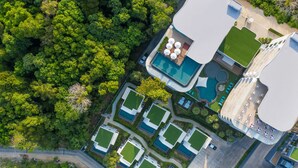 An aerial view of a resort with multiple swimming pools, lush greenery, and a modern architectural design. - Utopia Naiharn (Rawai)