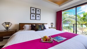 A hotel room with a large bed, a fruit platter, a magazine, and a view of palm trees through the window. - Baan Benjamart (Koh Samui)