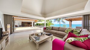 A spacious living room with a large sofa, a coffee table, and a view of the ocean. - Baan Benjamart (Koh Samui)