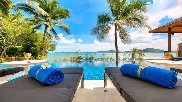 A poolside lounge with two sunbeds, a glass of drink, and a view of the sea. - Baan Benjamart (Koh Samui)