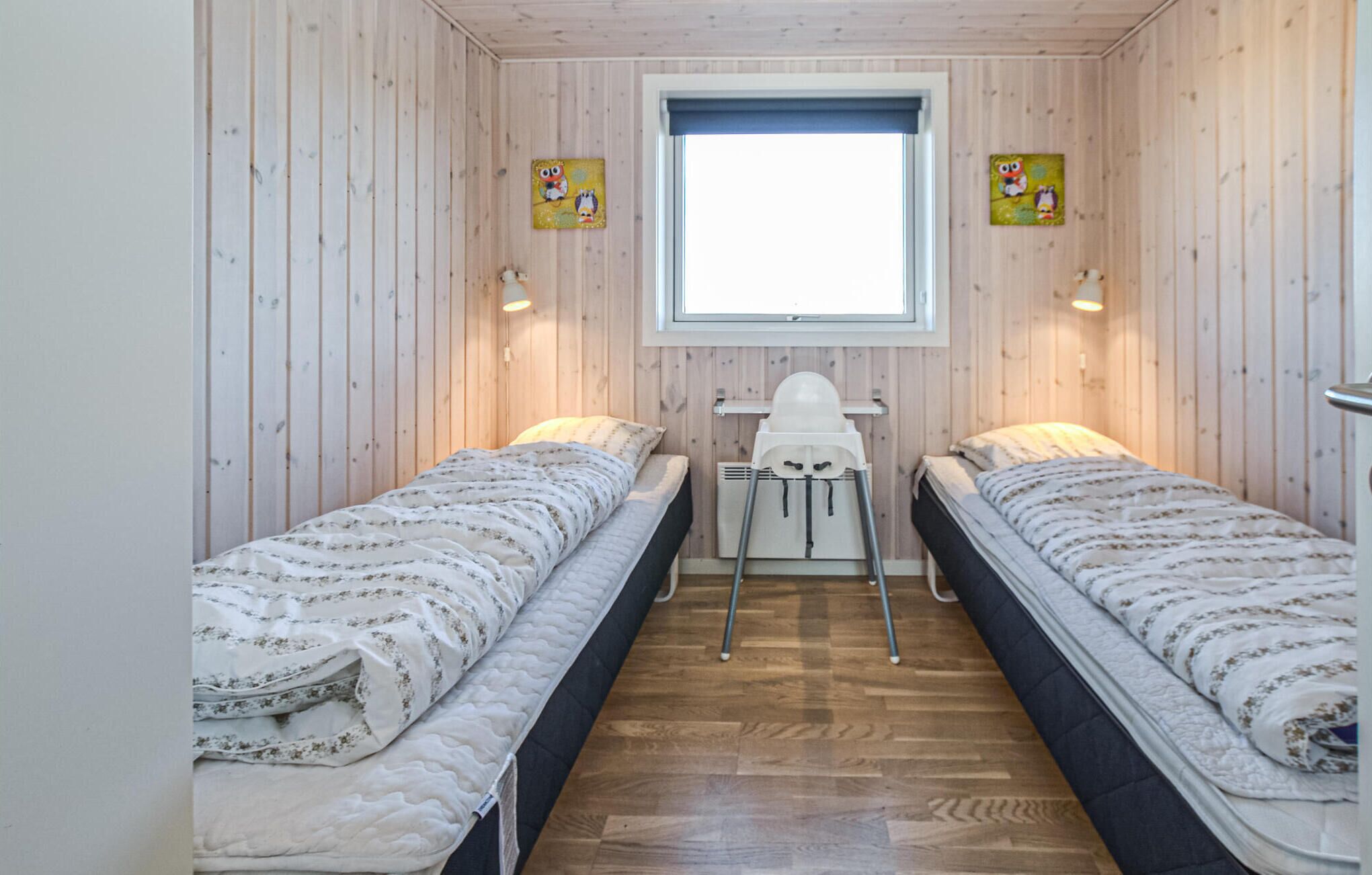 Una habitación con dos camas, una ventana y paredes de madera.