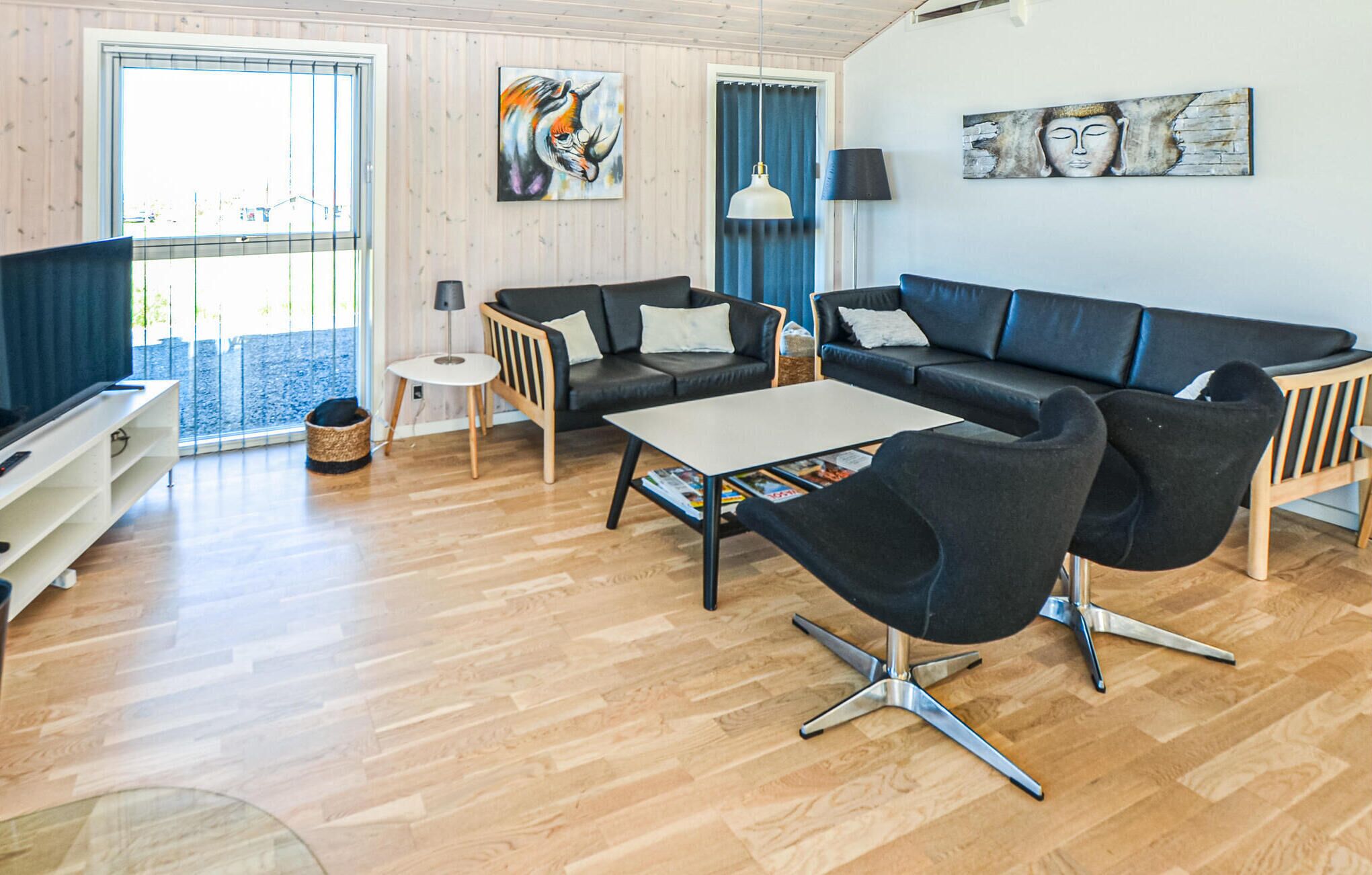 Ein modernes Wohnzimmer mit Sofa, Sesseln, Couchtisch und Kunstwerken an den Wänden.