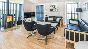 A modern living room with a fireplace, black leather sofas, a TV, and a dining area. - 4 bedroom gorgeous home in Nordborg (Nordborg)