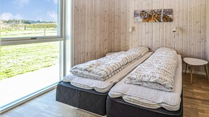 A bedroom with two beds, a wooden wall, a painting of tigers, and a view of a green landscape. - 4 bedroom gorgeous home in Nordborg (Nordborg)