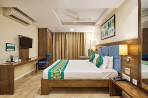 Una habitación de hotel con cama, mesita de noche, escritorio, silla y televisor.