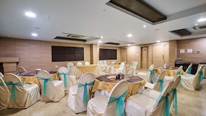 A conference room with tables and chairs, wooden panel walls, and ceiling lights. - Treebo Premium PL Grand, Visakhapatnam (Visakhapatnam)