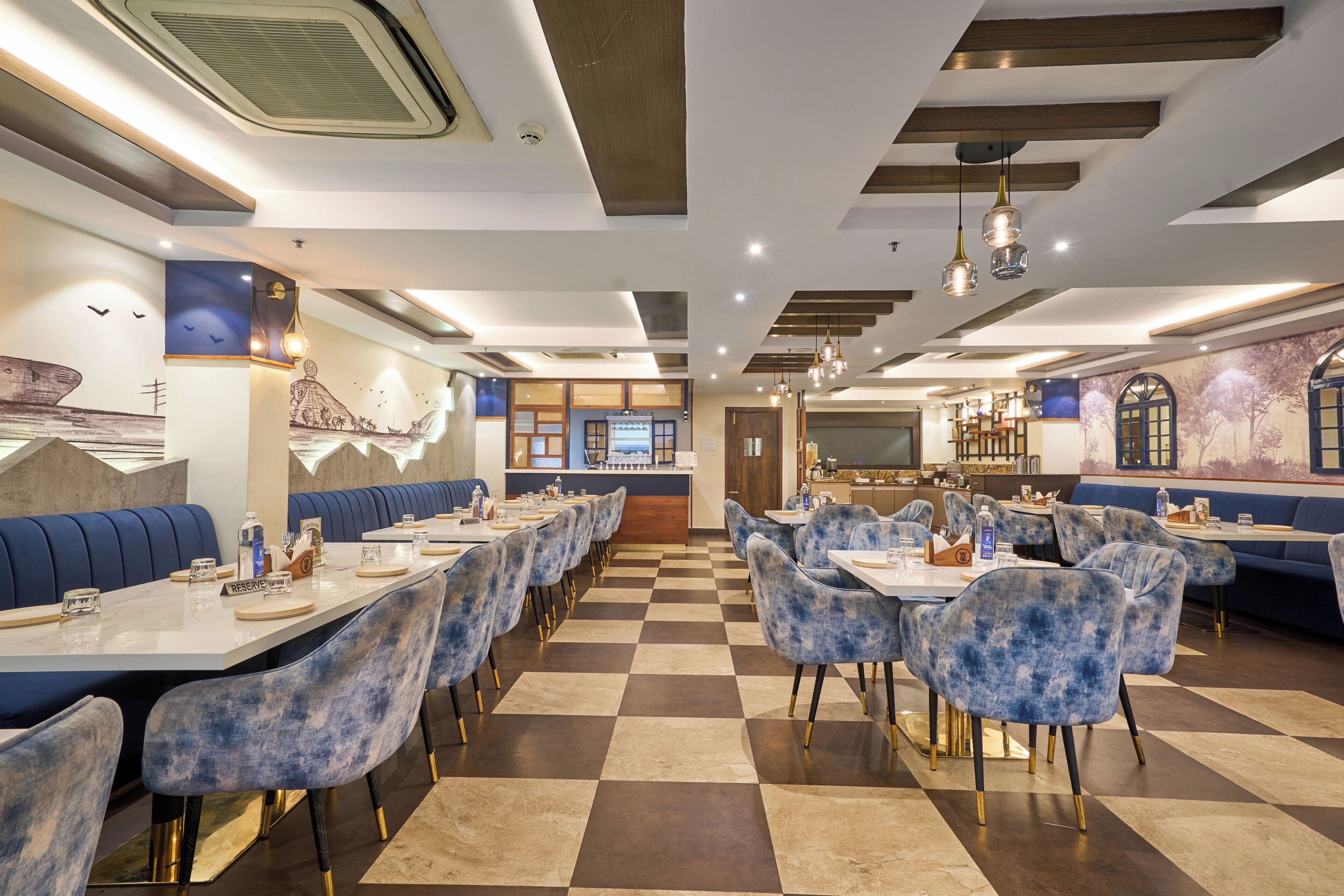 A restaurant with checkered flooring, blue upholstered booths, and a central bar area.