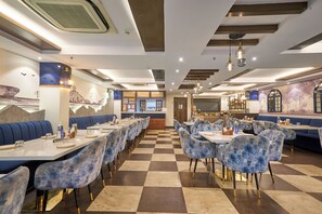 Un restaurante con suelo a cuadros, cabinas tapizadas en azul y una zona de bar central.