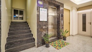 A hotel lobby with a marble staircase, an elevator, a reception desk, and a potted plant. - Treebo Premium PL Grand, Visakhapatnam (Visakhapatnam)