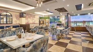 A restaurant with checkered flooring, blue upholstered chairs, and a bar area with a view. - Treebo Premium PL Grand, Visakhapatnam (Visakhapatnam)