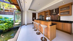 Una cocina moderna con una isla grande, taburetes de bar y vistas a un jardín con fuente de agua.