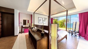 Un dormitorio moderno con cama con dosel, un escritorio con silla, un ventanal con vista al mar y un balcón con una silla.