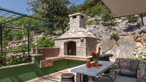 Patio esterno con forno a pietra, un tavolo con bevande e mobili in vimini.