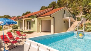 Area piscina con una vasca, sedie a sdraio rosse e un ombrellone blu.