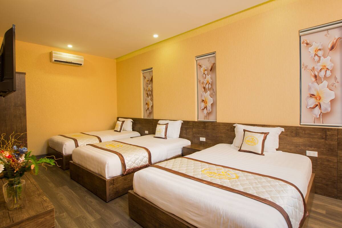 Habitación de hotel con tres camas, cabeceros de madera y suelo de madera.
