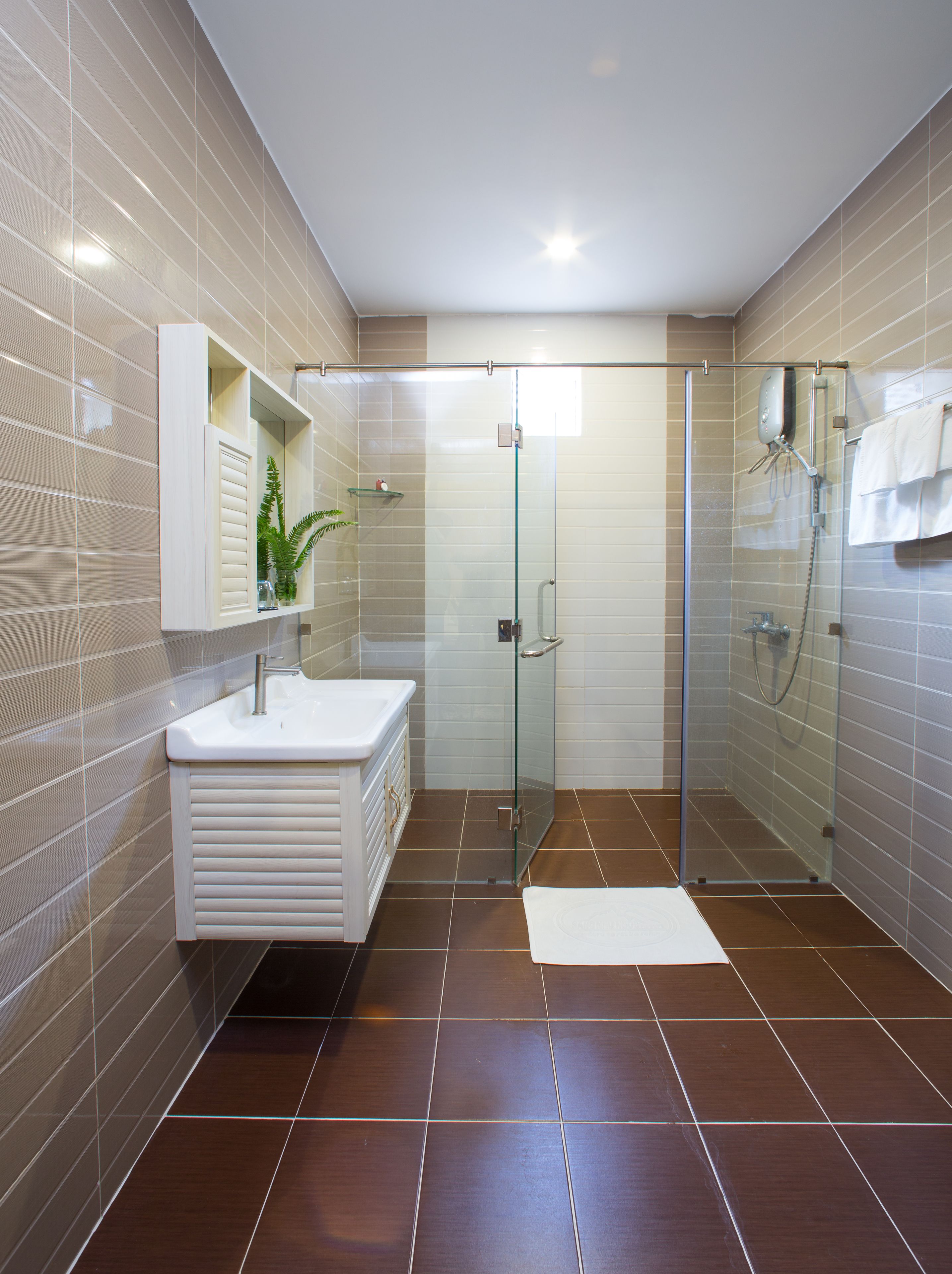 A modern bathroom with a glass-enclosed shower, a white vanity, and a mirror above the sink.