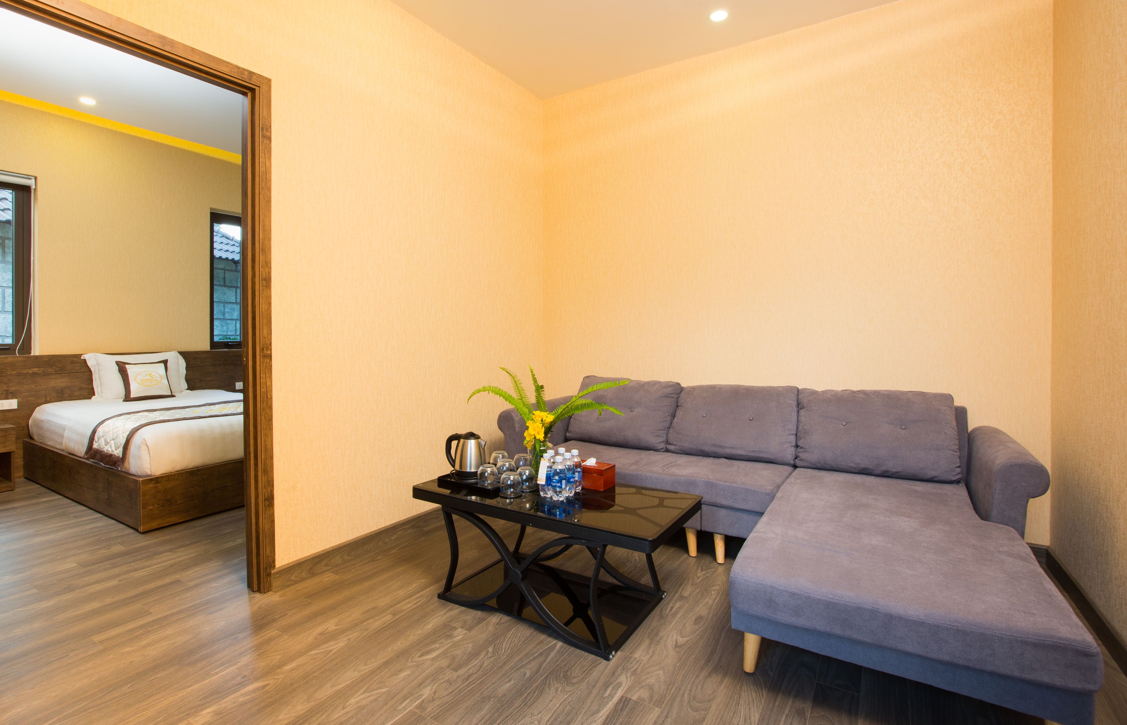 A modern room with a bed, a gray sofa, and a coffee table with a vase of flowers.