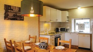 Een gezellige keuken met witte kastjes, een eettafel gedekt voor vier personen en een hangende lamp.