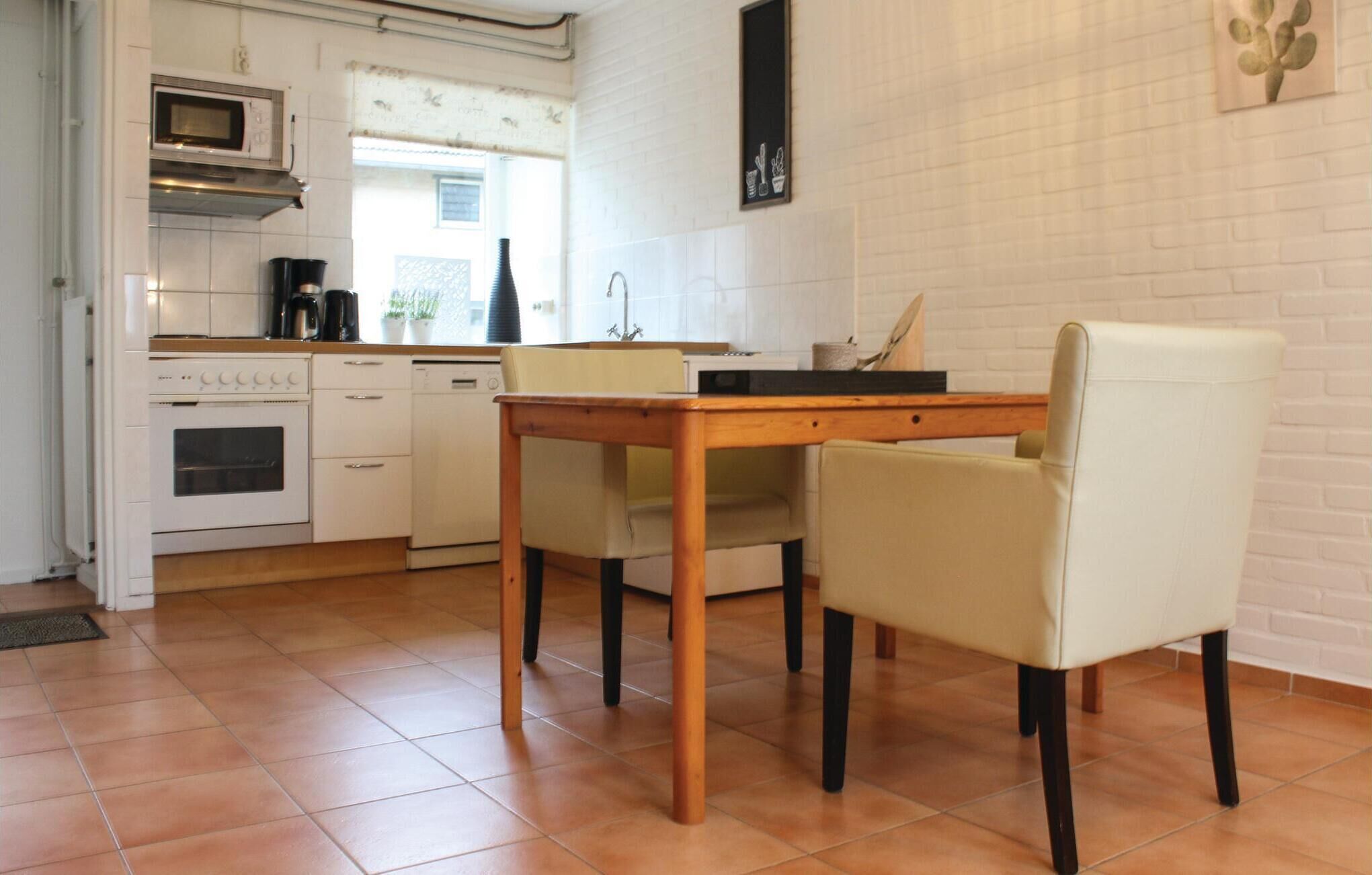 Une cuisine avec une table en bois et deux chaises, un four à micro-ondes, une cuisinière et un évier.