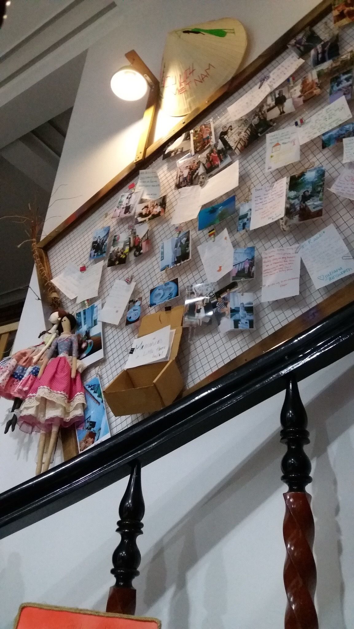 Portaikko, jonka seinää koristavat valokuvat, muistiinpanot ja nukke.