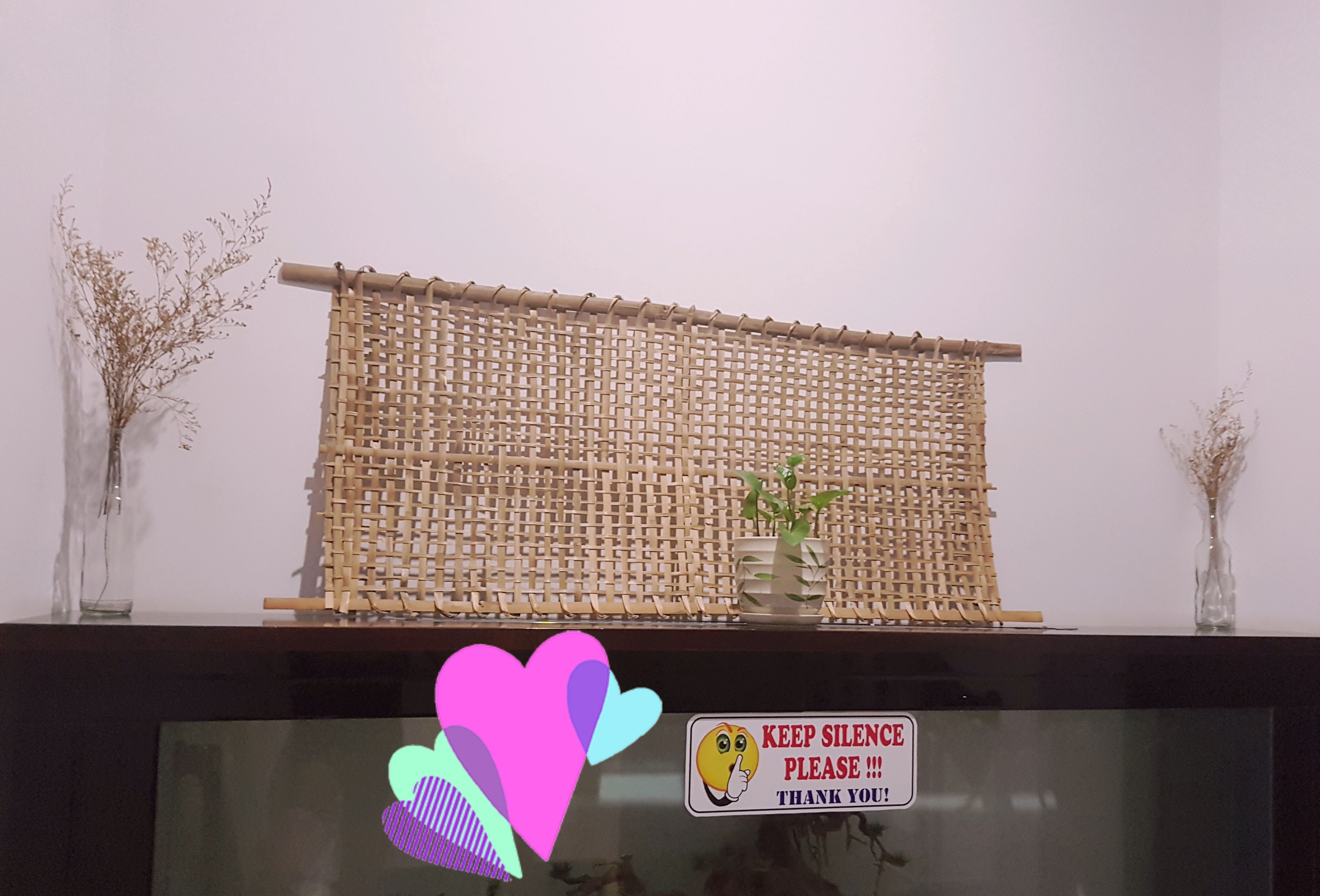 A room with a woven partition, a small potted plant, and a 'Keep Silence Please' sign.