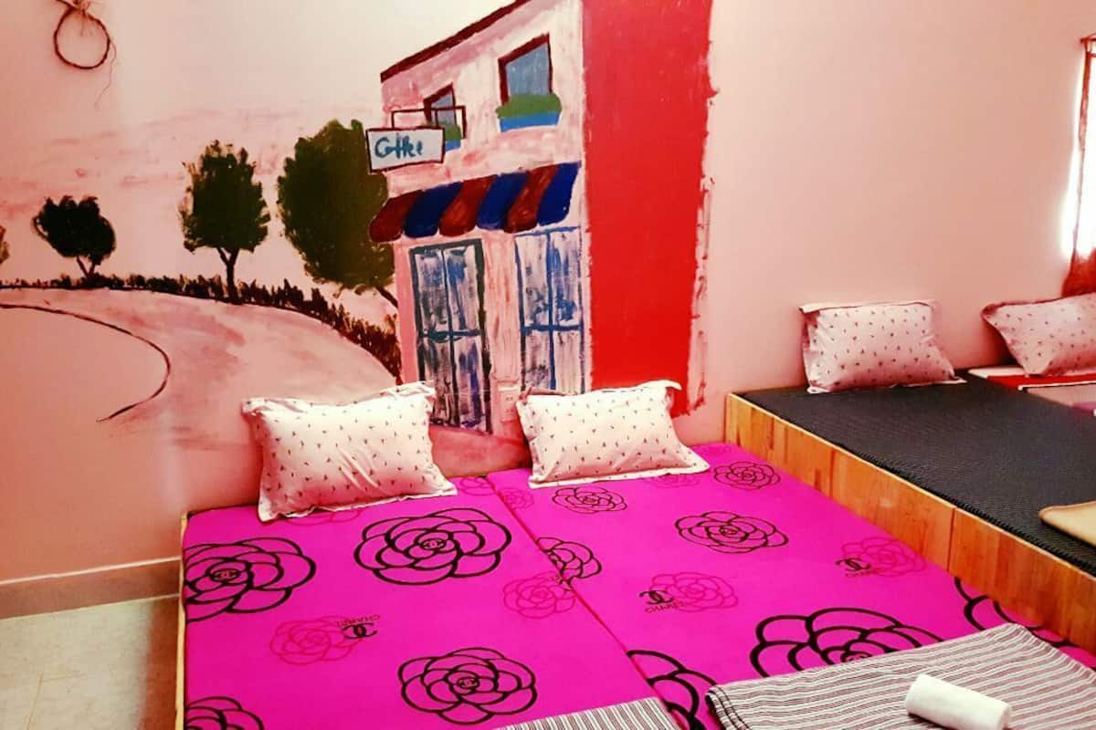 Ein Zimmer mit einem Bett, Kissen, einem Fenster und Wandgemälde.
