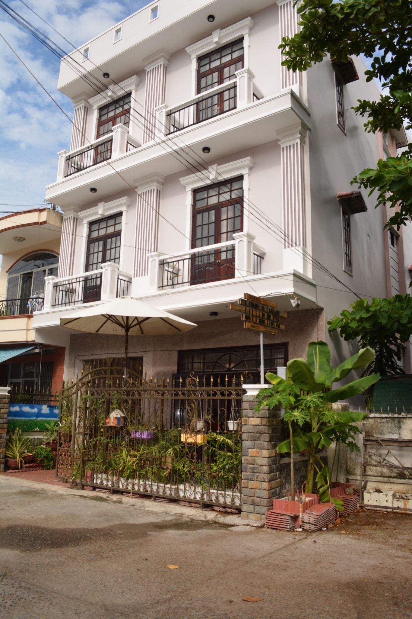 A multi-story building with a balcony, a gated entrance, and a signboard.