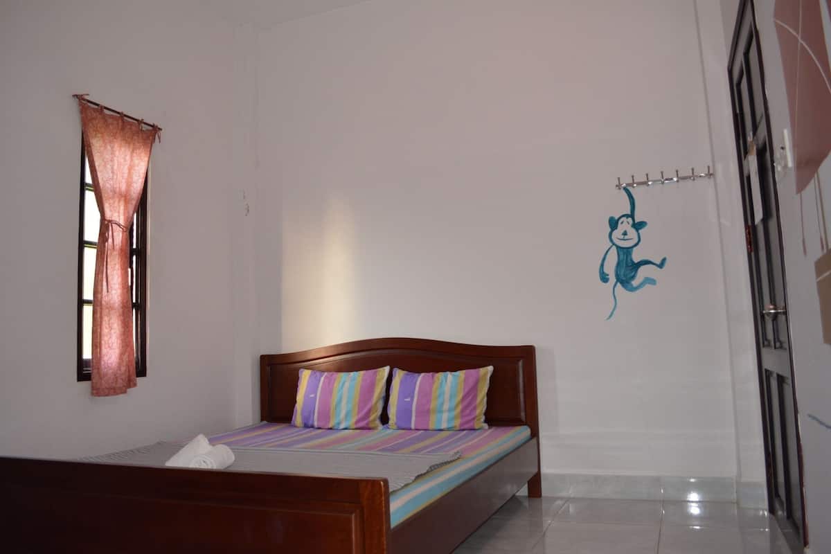 Ein Schlafzimmer mit Bett, Fenster mit Vorhängen, Wand mit Wanddekoration und Tür.