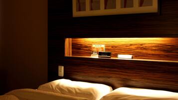 A hotel room with a wooden headboard, a bedside table with a lamp, and a framed picture above the bed.