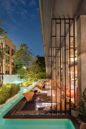 A poolside area with seating, a view of the building, and a clear sky.