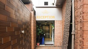 A reception area with a sign above the door, a potted plant, and a tiled floor. - Hotel Indralok Inn (Mawal)