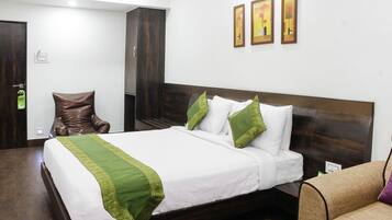 A neatly made bed with white and green linens, a wooden headboard, and a brown armchair.