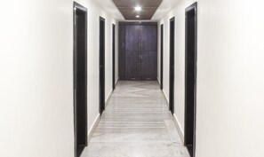 A hallway with white walls, black-framed doors, and a marble floor.