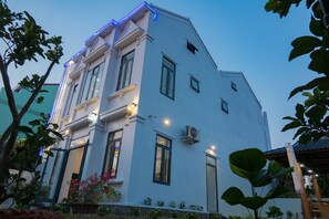 Un edificio moderno de dos pisos con fachada blanca, ventanas amplias y techo plano.
