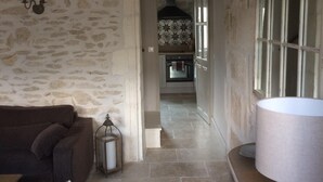 A stone-walled room with a dark brown sofa, a white lamp, and a tiled floor. - In the heart of downtown St Rémy de Provence, the Mas D'Oscar! (Saint-Rémy-de-Provence)
