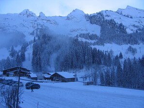 Paisaje montañoso cubierto de nieve con cabañas de madera y un telesilla.
