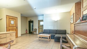 Ein geräumiges Wohnzimmer mit einer Couch, einem Holzschrank, einem Sessel und einem Klavier.