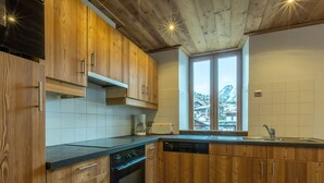 Eine moderne Küche mit Holzausbau, einem Einbauofen und einem Fenster mit Blick auf eine Berglandschaft.