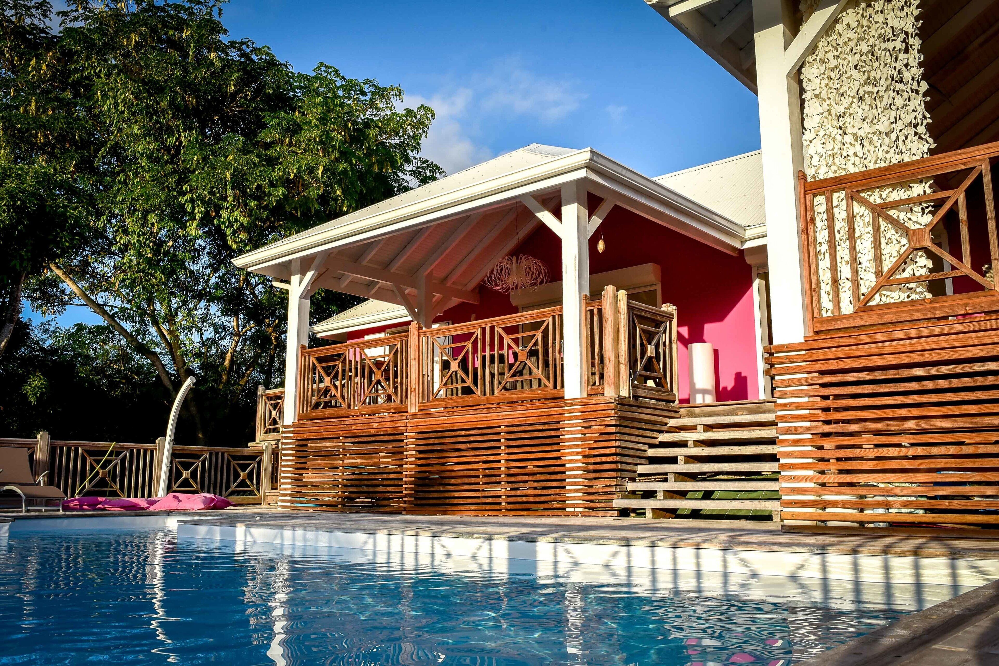 A poolside area with a wooden deck, a covered seating area, and a pool.
