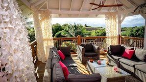 A covered outdoor seating area with wicker furniture, a wooden deck, and a view of lush greenery. - 5* Villa with Secured Pool and Beautiful Tropical Garden (SAINT FRANCOIS)