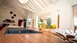 A modern kitchen with a wooden countertop, a built-in sink, and hanging pendant lights. - 5* Villa with Secured Pool and Beautiful Tropical Garden (SAINT FRANCOIS)