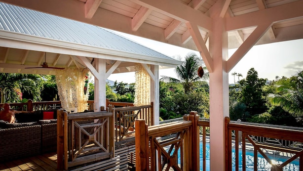 A covered outdoor area with a pool, wooden deck, and lounge seating. - 5* Villa with Secured Pool and Beautiful Tropical Garden (SAINT FRANCOIS)