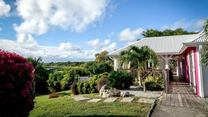 A house with a covered porch, surrounded by lush greenery and a clear sky. - 5* Villa with Secured Pool and Beautiful Tropical Garden (SAINT FRANCOIS)