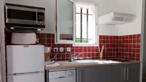 Una cocina con microondas, refrigerador, lavamanos y ventana.