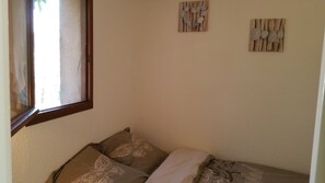 Une pièce comprenant un lit, une fenêtre et deux éléments décoratifs sur les murs.