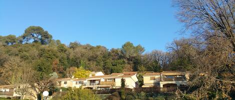 A hillside residential area with terraced houses, lush greenery, and a clear blue sky.